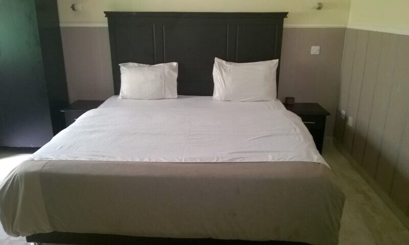 Bed with a dark wood headboard in the One Bed Superior room at Heights Hotels Victoria Island